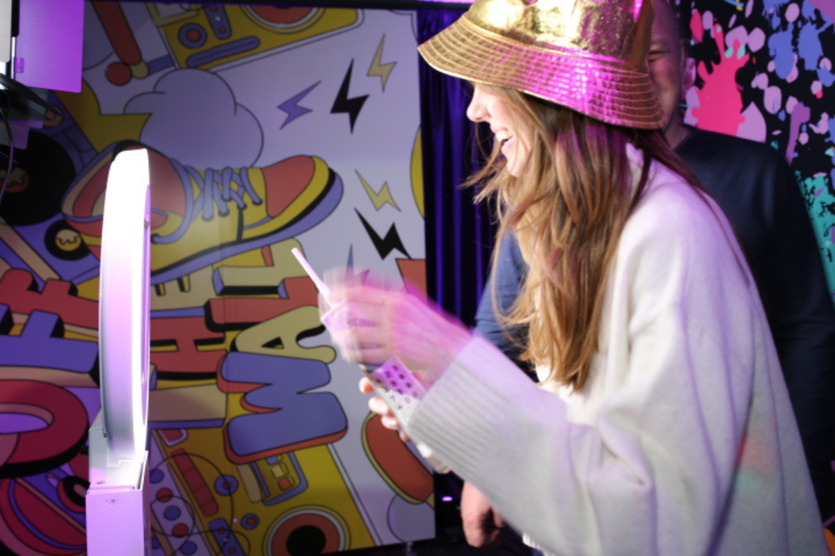Guest using eco-friendly photo booth with SMS image delivery at a corporate event in Phoenix, Arizona, featuring vibrant branded backdrop and sustainable event marketing setup by MISGIF Photo Booths